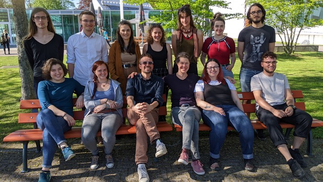 Gruppenfoto der Teilnehmenden, die auf dem Campus Offenburg auf einer Bank sitzen beziehungsweise hinter dieser stehen